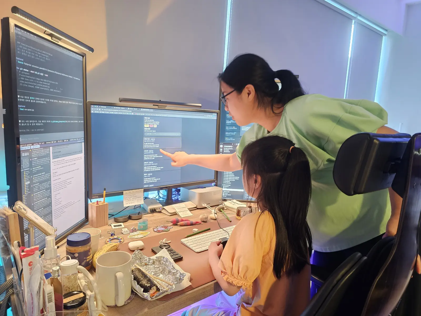 Seorang kru menunjuk layar monitor sambil menjelaskan sesuatu ke anak itu.